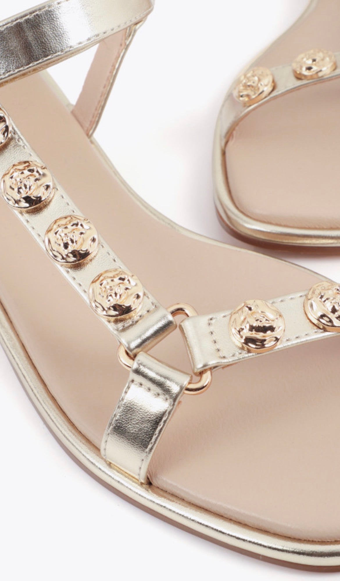 Dettaglio borchie tonde dorate su cinturino a T sandalo flat oro Lola Casademunt