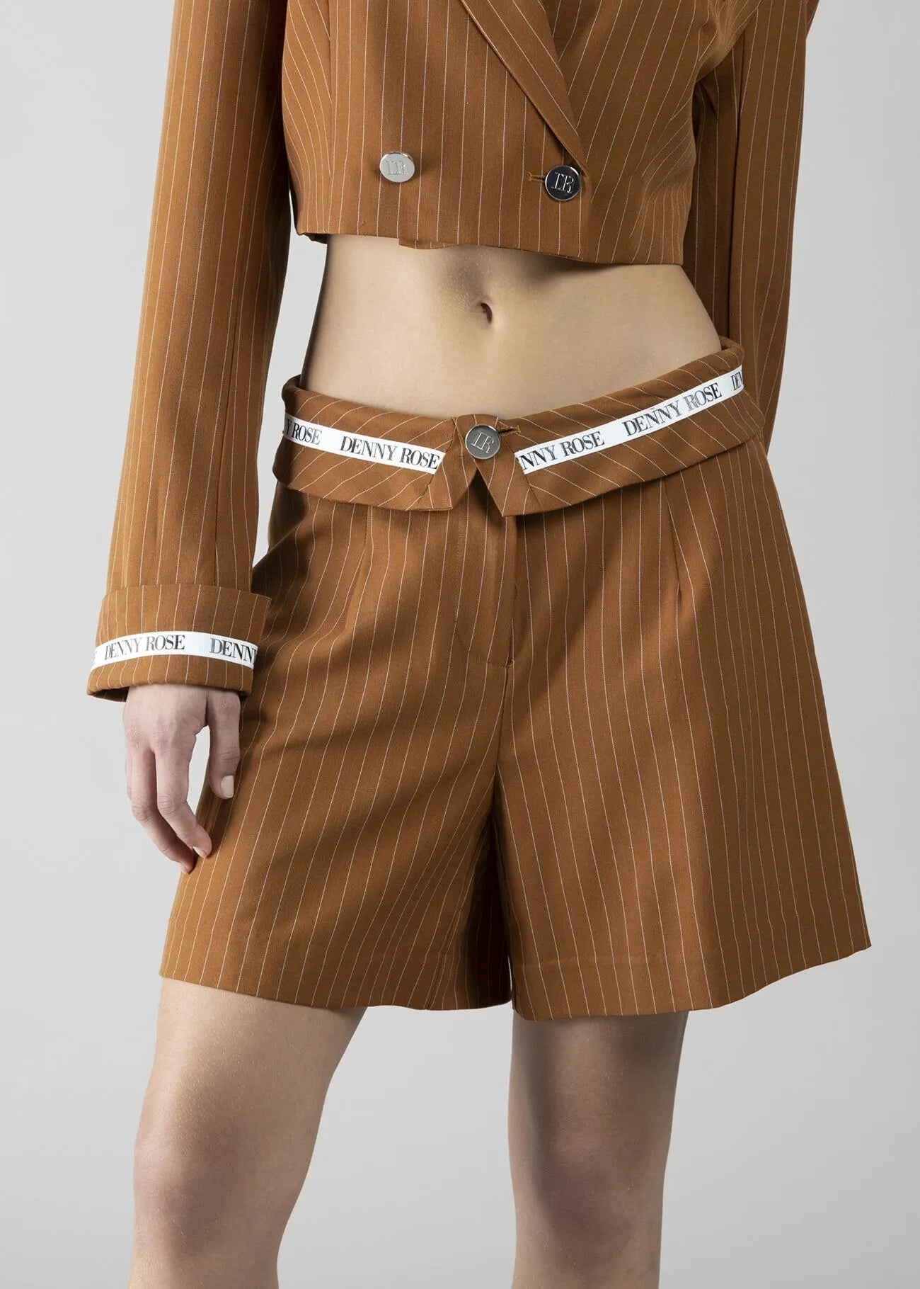 Foto 1: "Shorts gessato cuoio Denny Rose - vista frontale su modella con patta a risvolto, nastro logato in vita e gamba ampia"